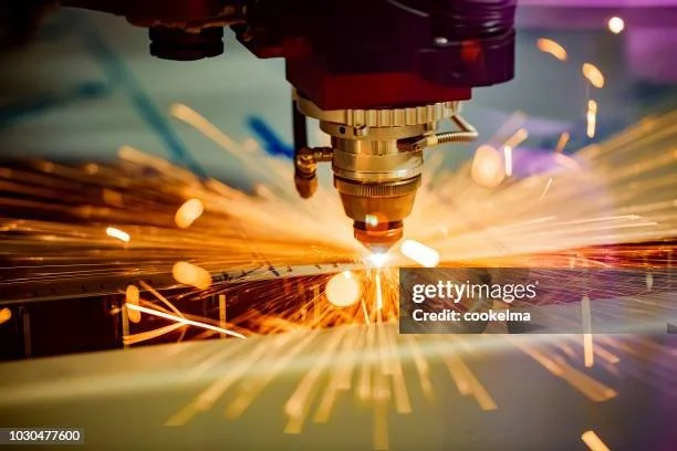 A robotic welding machine fusing metal parts with sparks flying during the welding process.