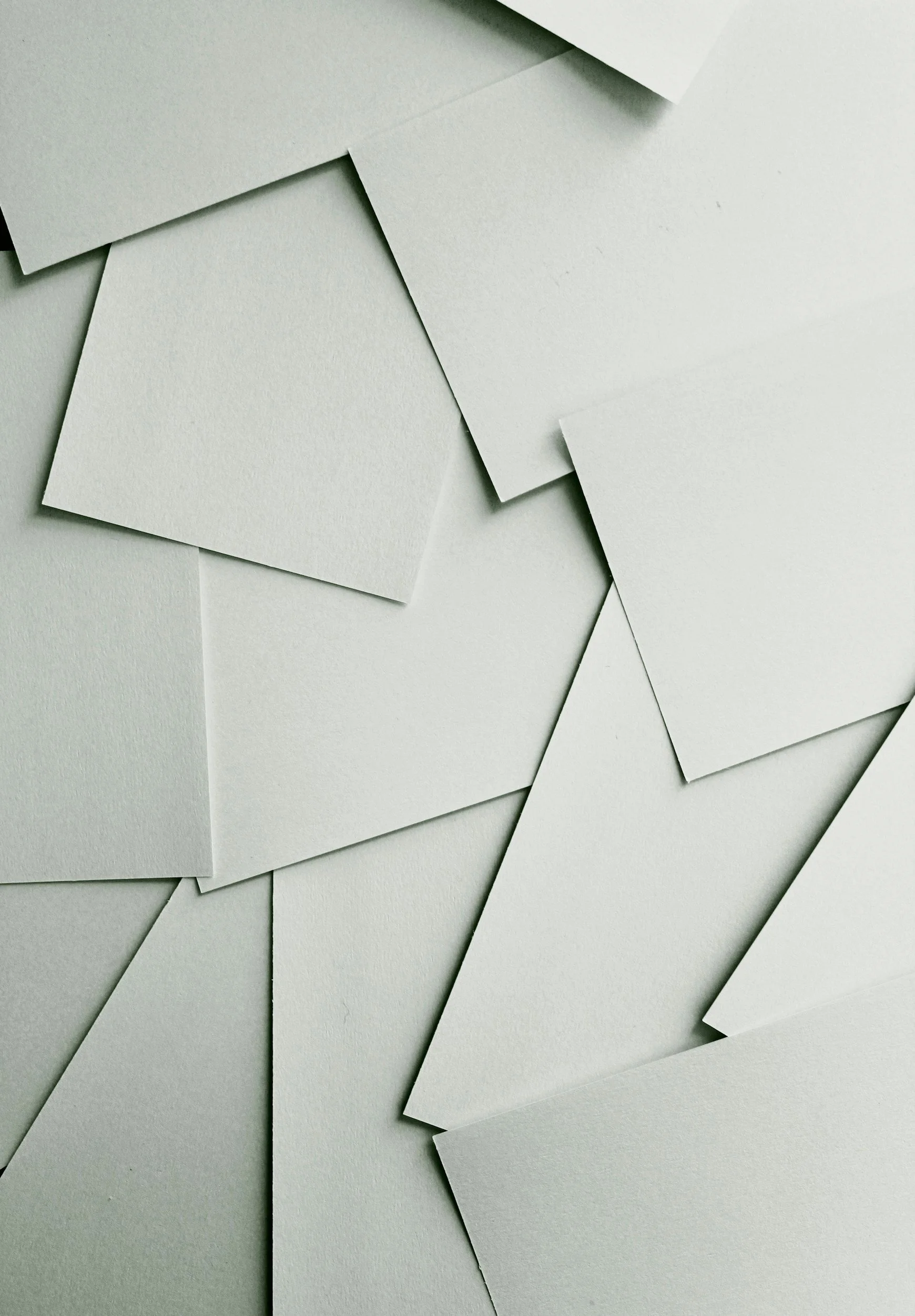 Multiple blank white sheets of paper overlapping each other and scattered on a surface.