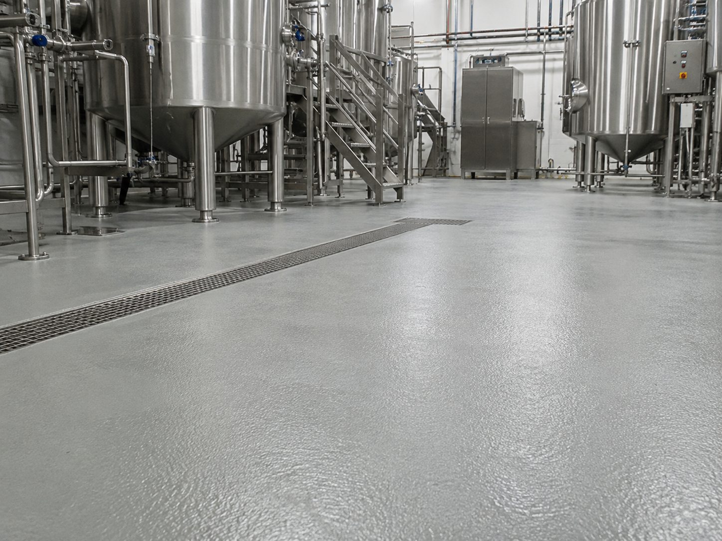 Empty industrial brewery or food processing plant with stainless steel tanks and piping.