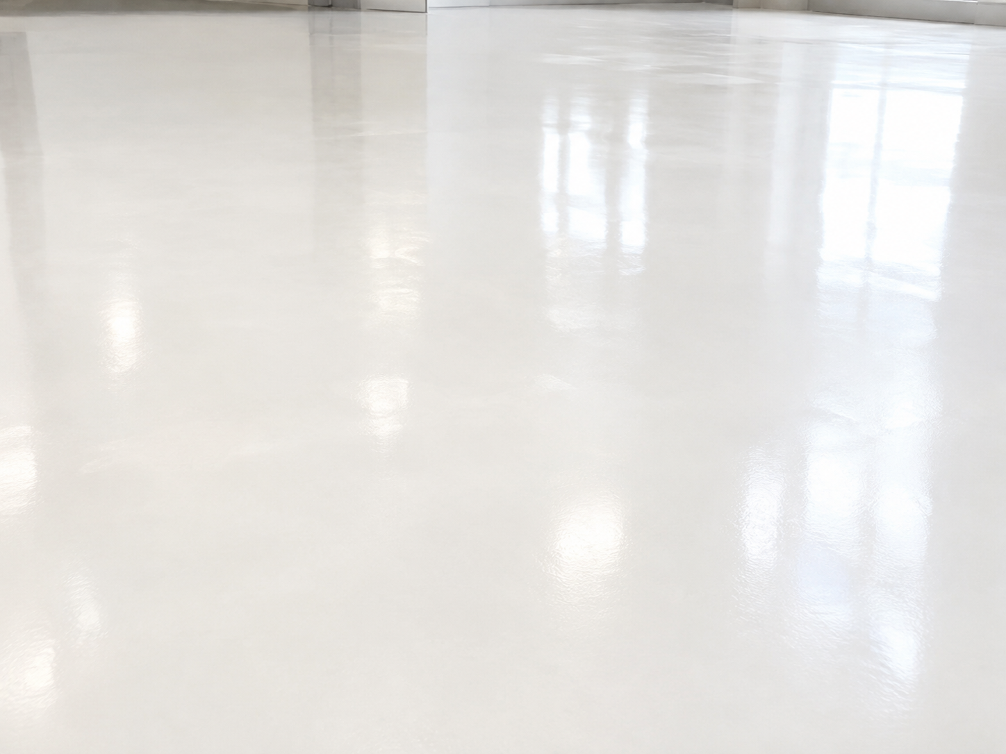 Empty, glossy, white tiled floor with reflections of windows and walls in the background.