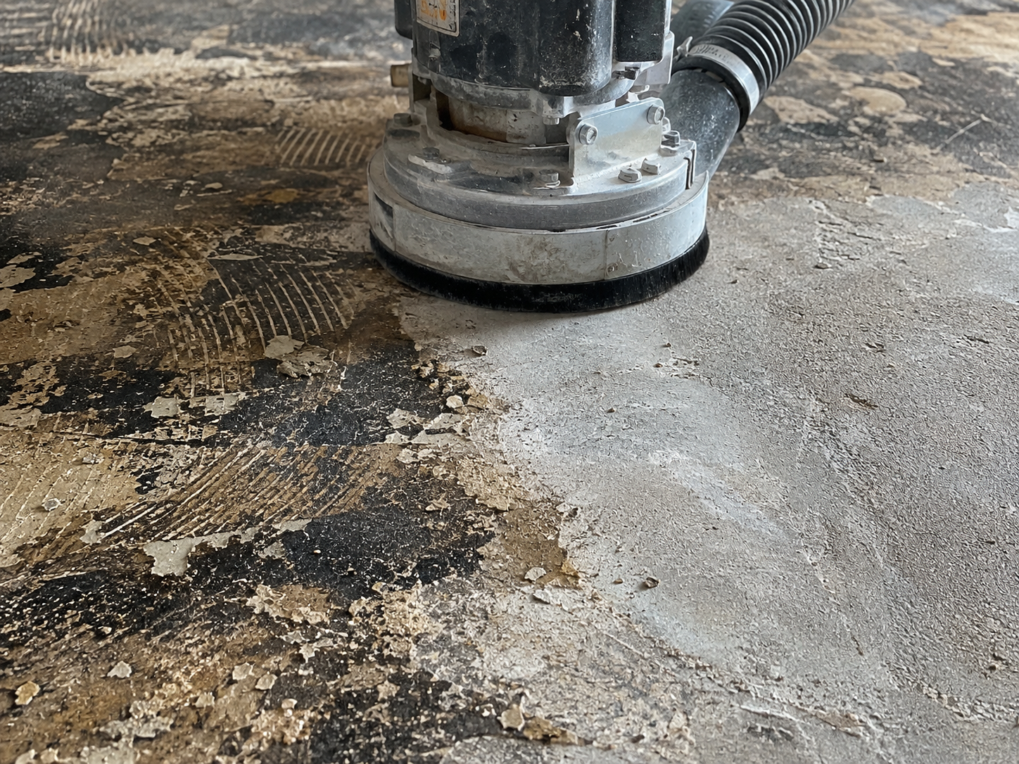 Close-up of a floor sander machine polishing a wooden floor with visible dust and debris.