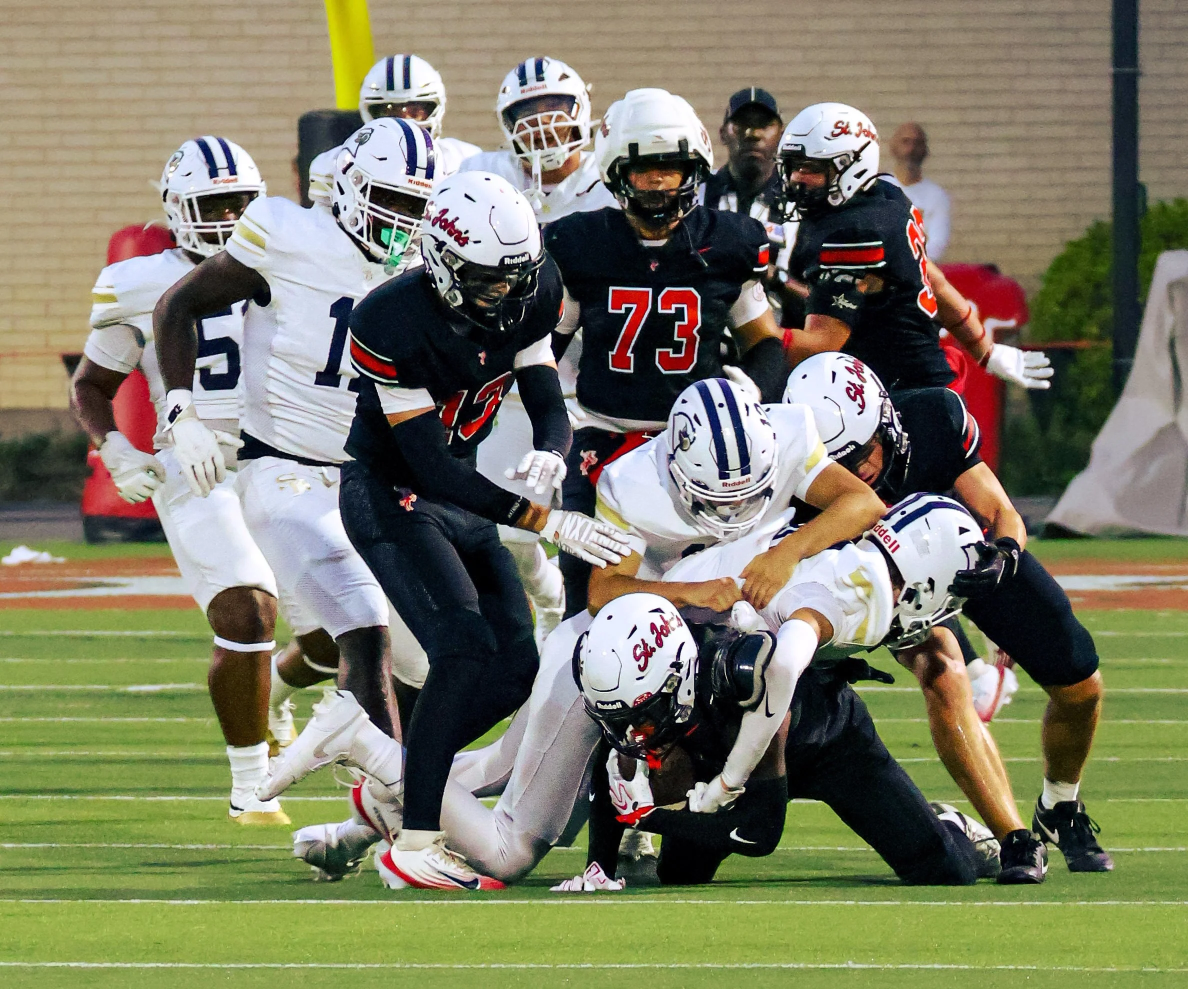 American football players in uniform engaging in a tackle during a game on a football field.