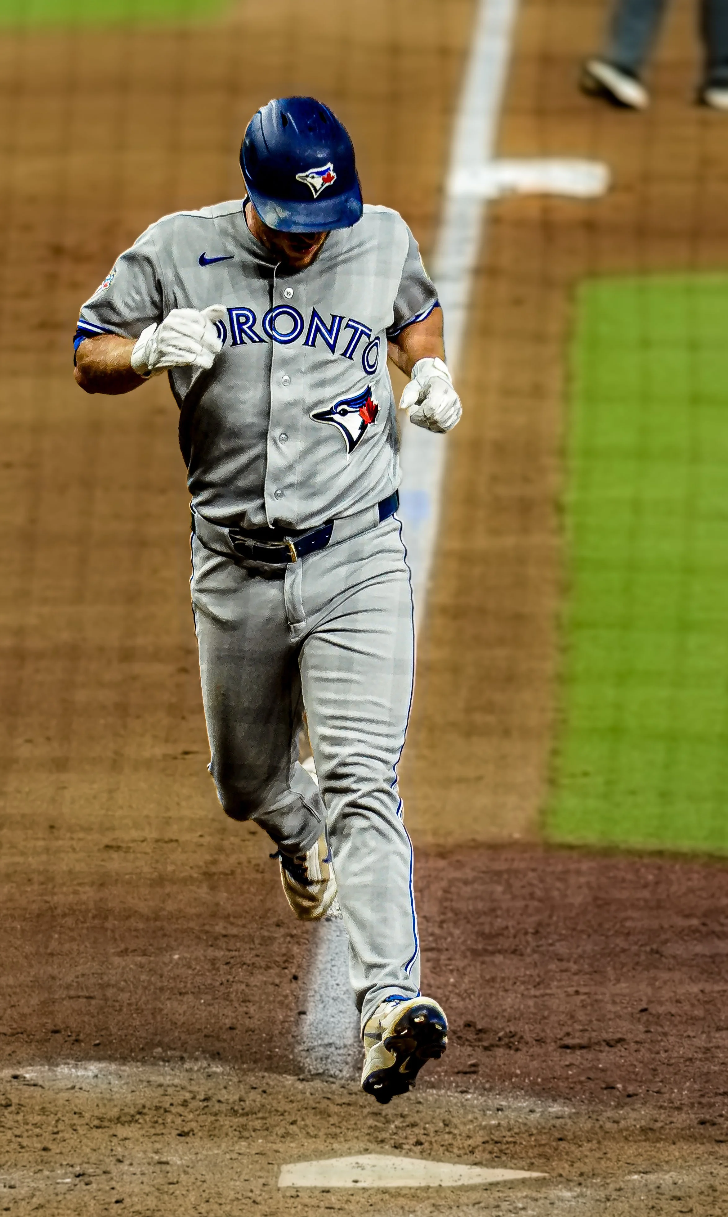 A baseball player from the Toronto Blue Jays running on the field near home plate during a game.