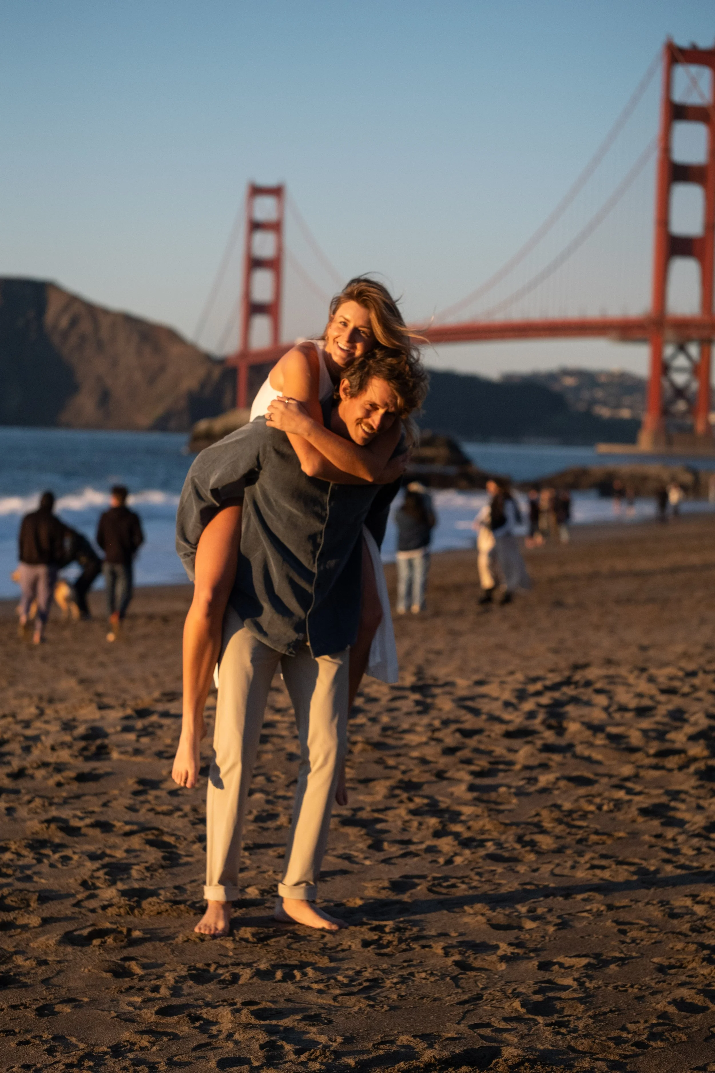 A couple on a beach near San Francisco, with the Golden Gate Bridge in the background during a couple's photoshoot.
