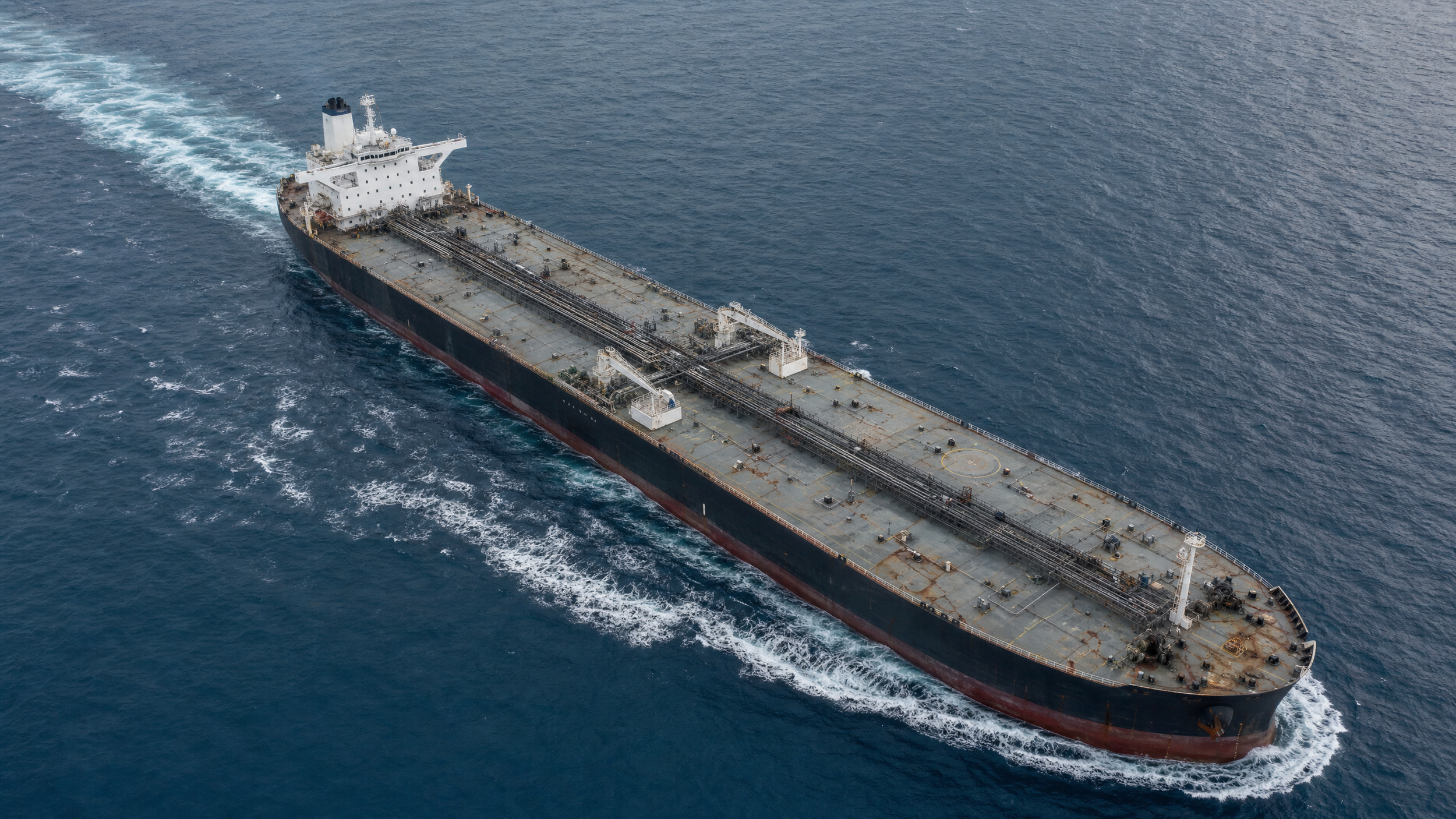 A large oil tankership sailing through open ocean water, leaving a wake behind it.