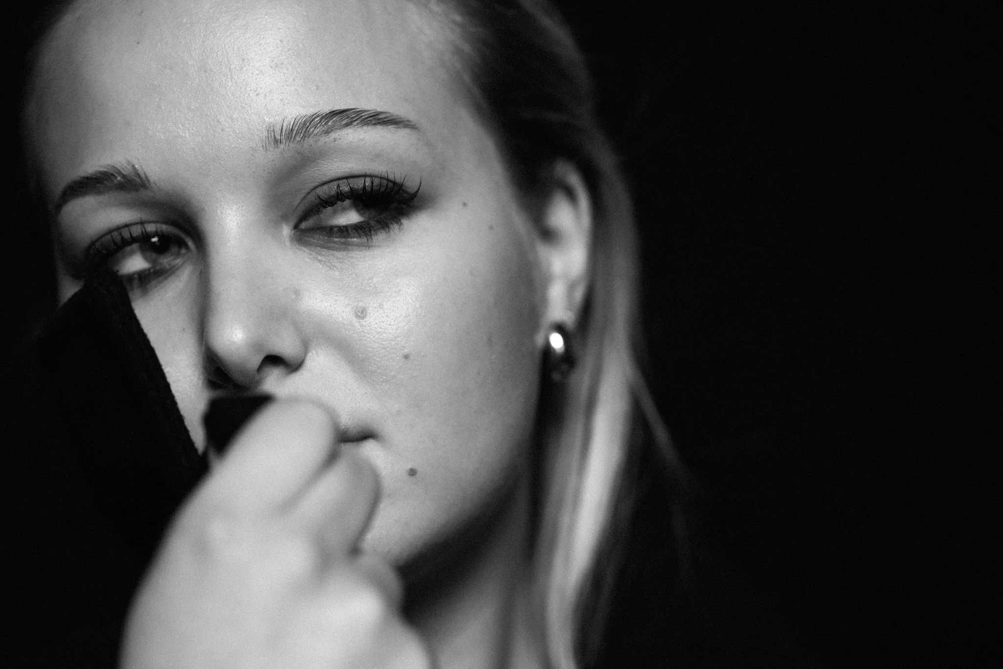 Schwarze und weiße Nahaufnahme eines Gesichts, fokus auf das Auge, das nach links blickt, mit sichtbaren Wimpern und Augenbrauen.