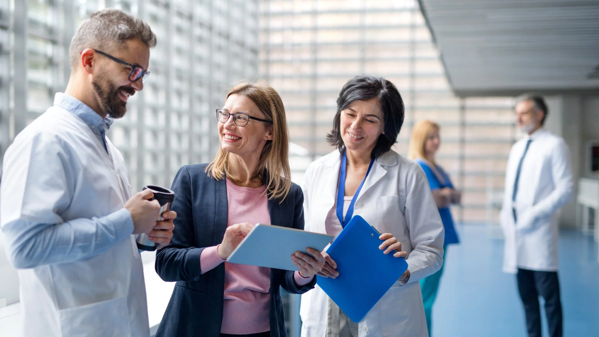 Group of medical professionals, including doctors and nurses, engaging in conversation and reviewing documents in a modern health facility.