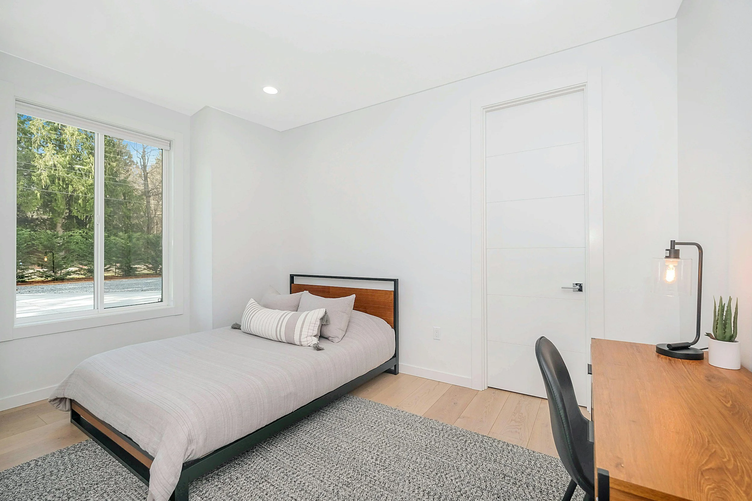 Furnished private bedroom with bed, desk, and natural light