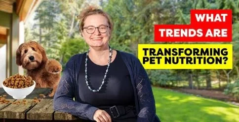 A woman smiling outdoors with a small brown dog and a bowl of pet food on a wooden surface, with a headline about pet nutrition trends.