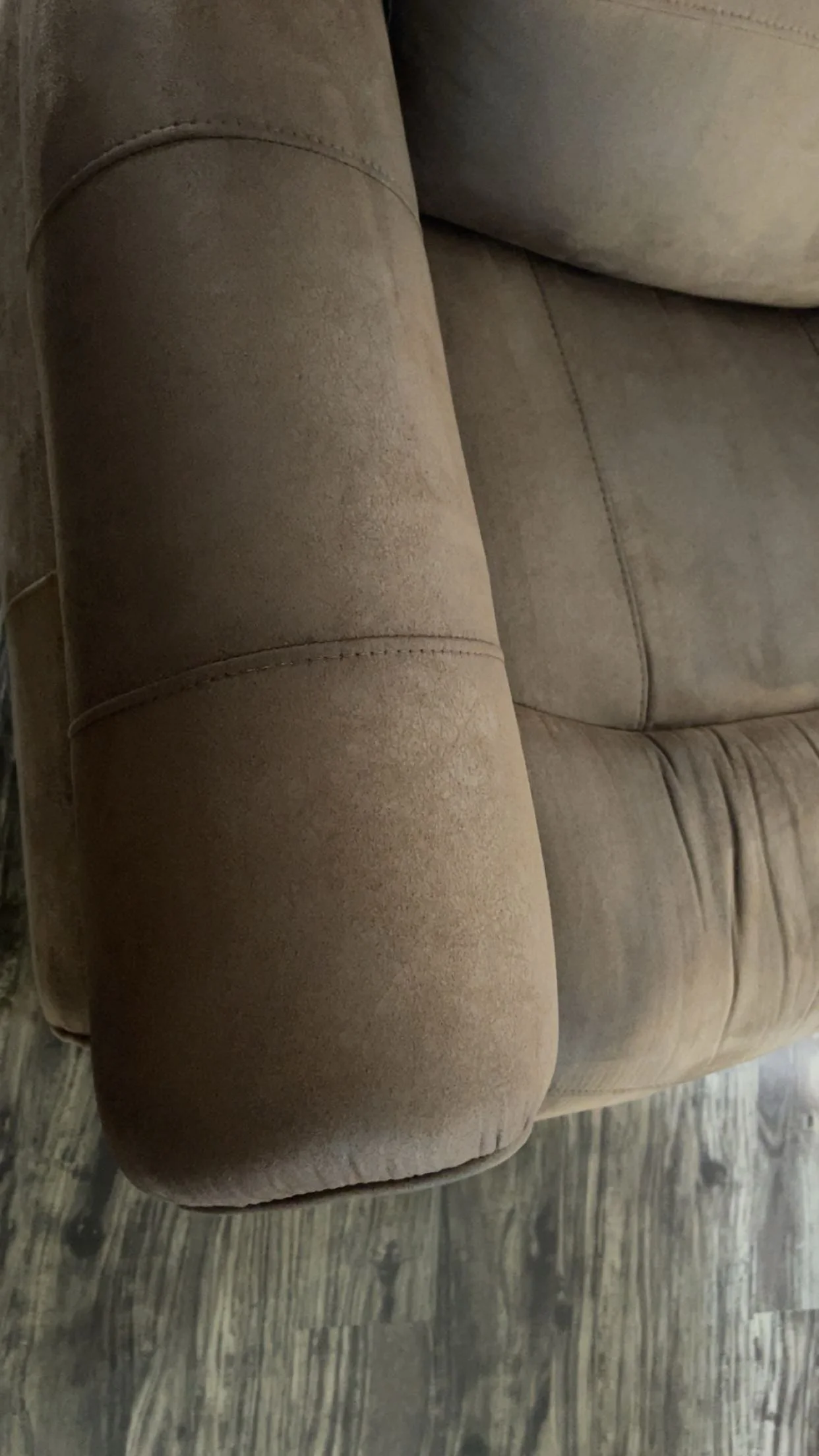 Close-up of a beige or tan upholstered sofa on a wooden floor.