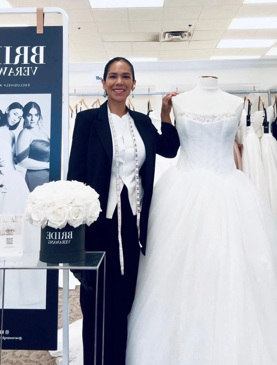 Alteration specialist standing beside a wedding gown during a professional bridal fitting.