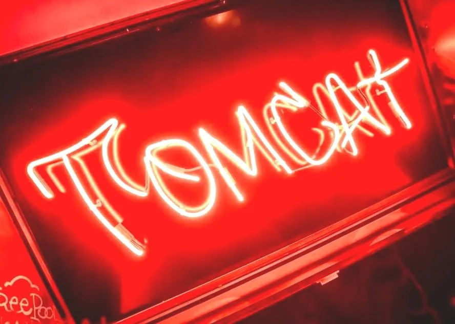 Red neon sign that reads 'TOMCAT'