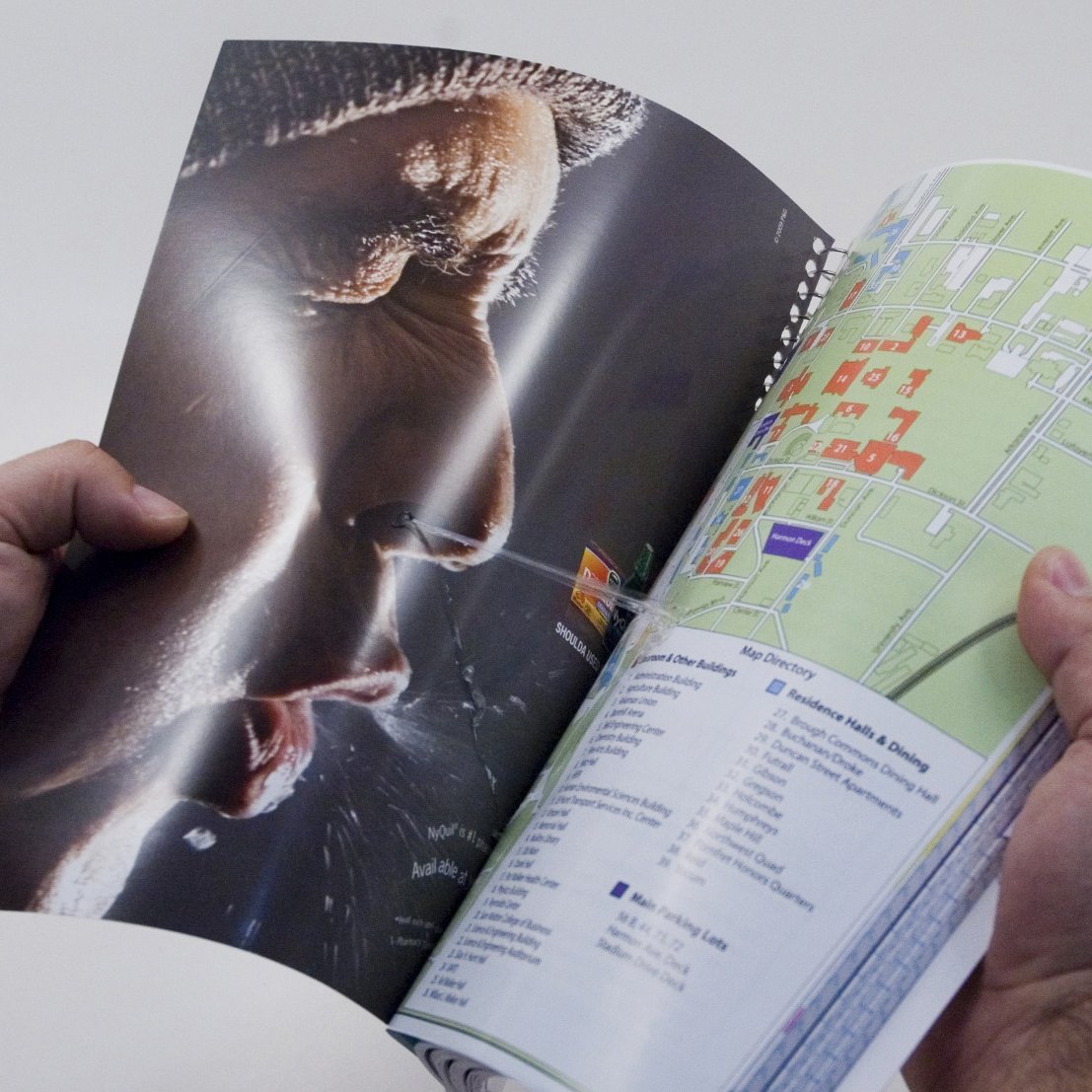 Close-up of the Vicks print ad: an open booklet with a campus map on one side and a man's face in profile on the other, a stretched string of booger spanning the fold between them.