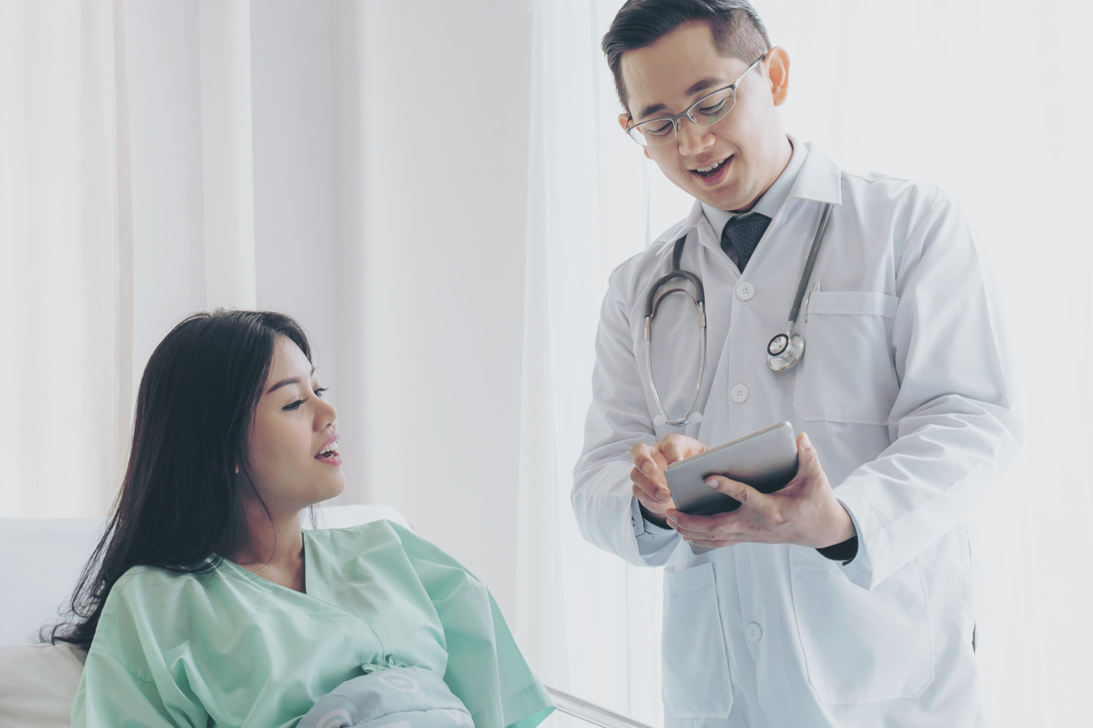 Doctor using a tablet to explain health information to a patient, representing Cogniss's ability to help health systems and providers create targeted digital health tools to improve patient outcomes.