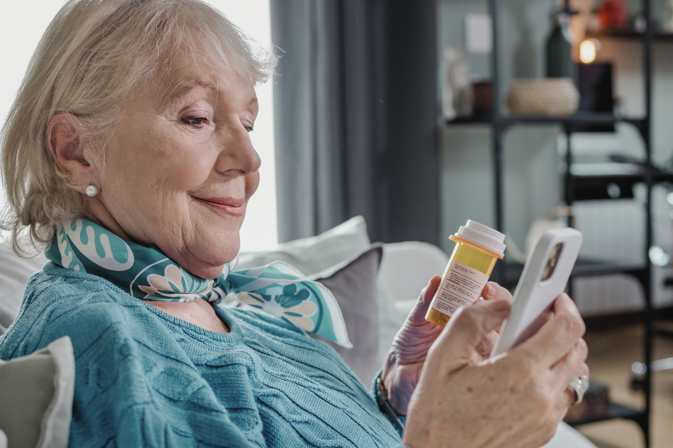 Senior woman holding a prescription bottle while using a smartphone, symbolizing how life science companies can collect real-world evidence and gain patient insights with digital health solutions.