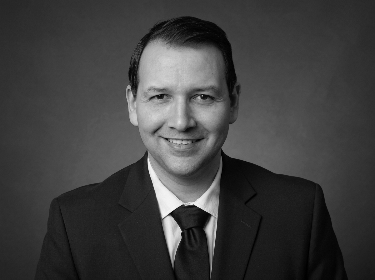 Black and white portrait of a man in a suit and tie smiling at the camera.