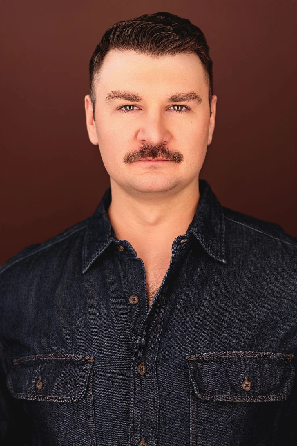 Chris Gallerani - Tenor, in a denim shirt against a brown backgroun. Headshot by Benjamin Rose Photography.