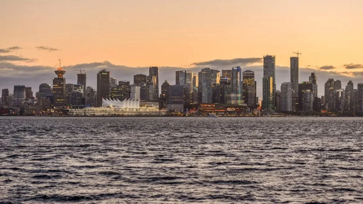 Seattle skyline at sunset with city buildings and waterfront in the foreground.