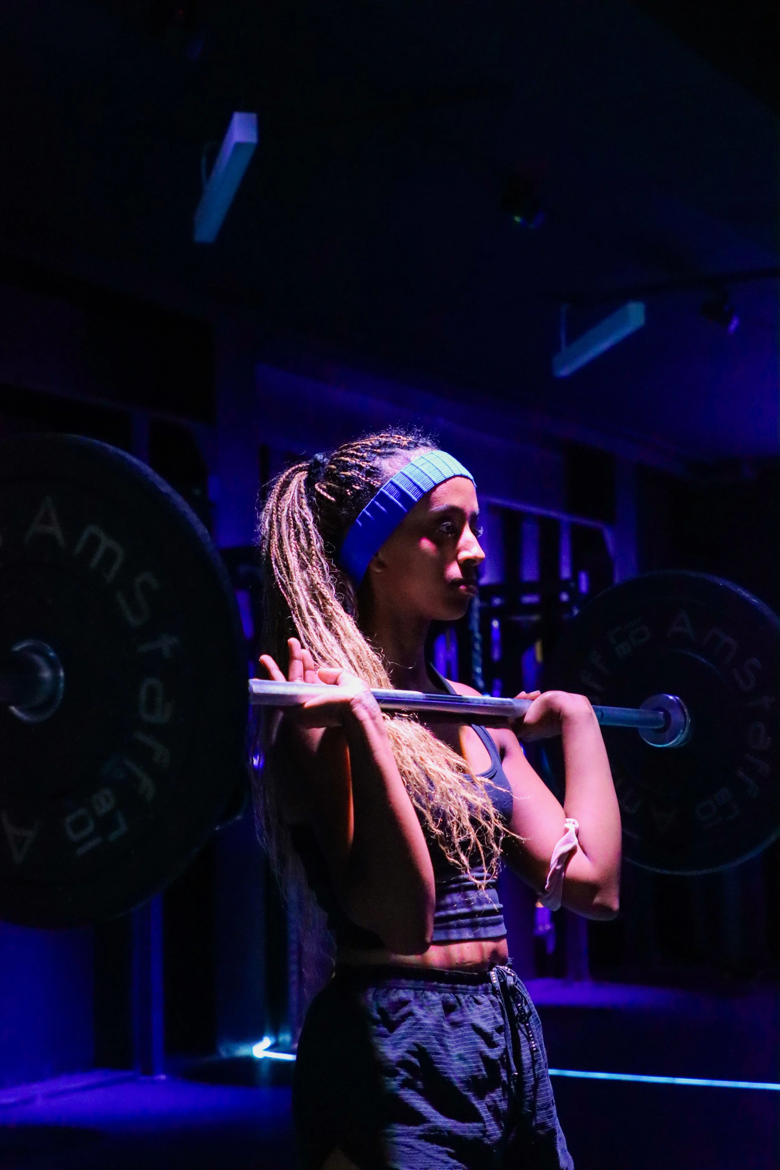 Performer with braided hair and a blue headband playing a flute under blue and purple stage lights
