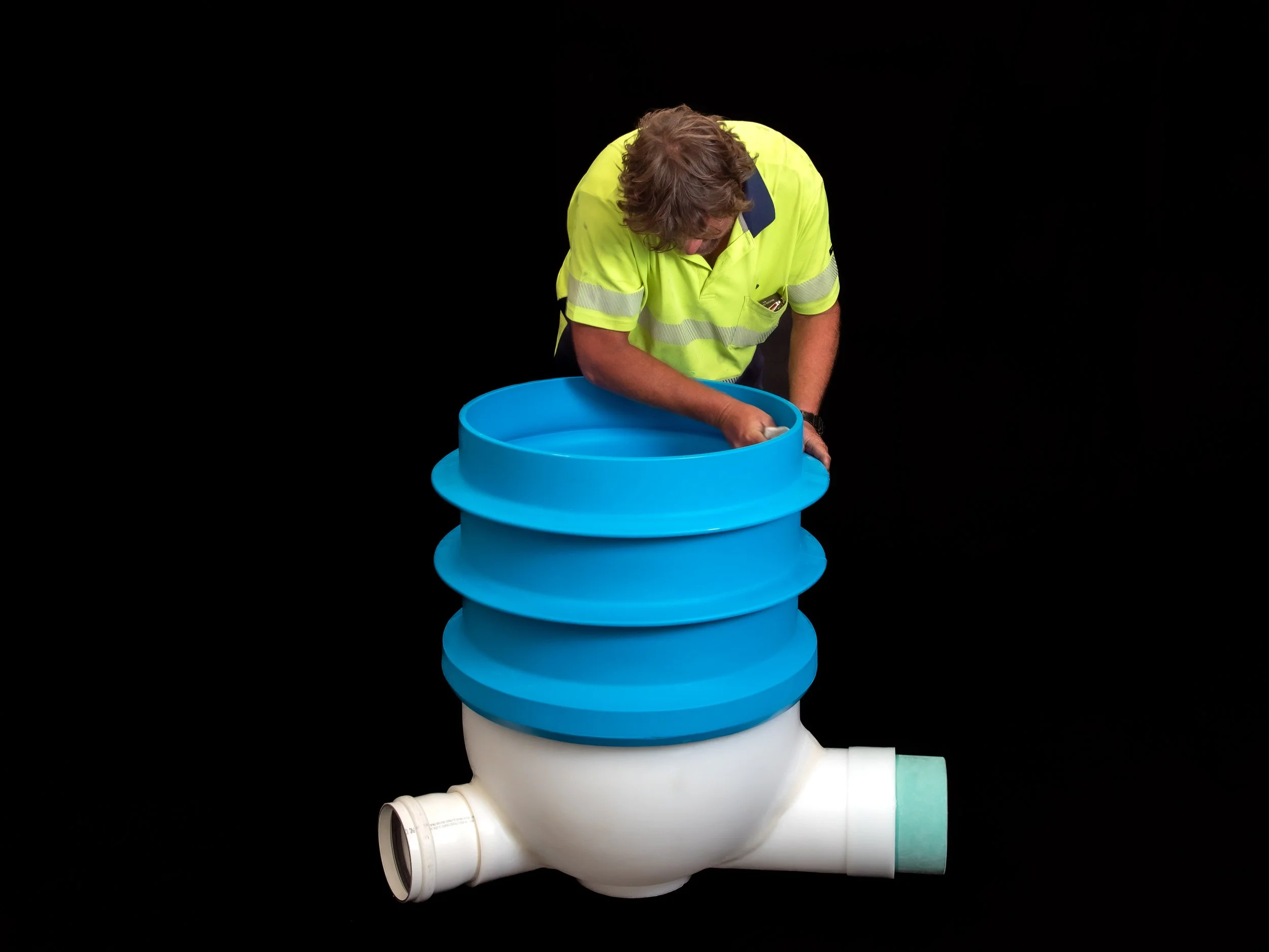 Worker inspecting a large blue industrial component photographed on location in a factory