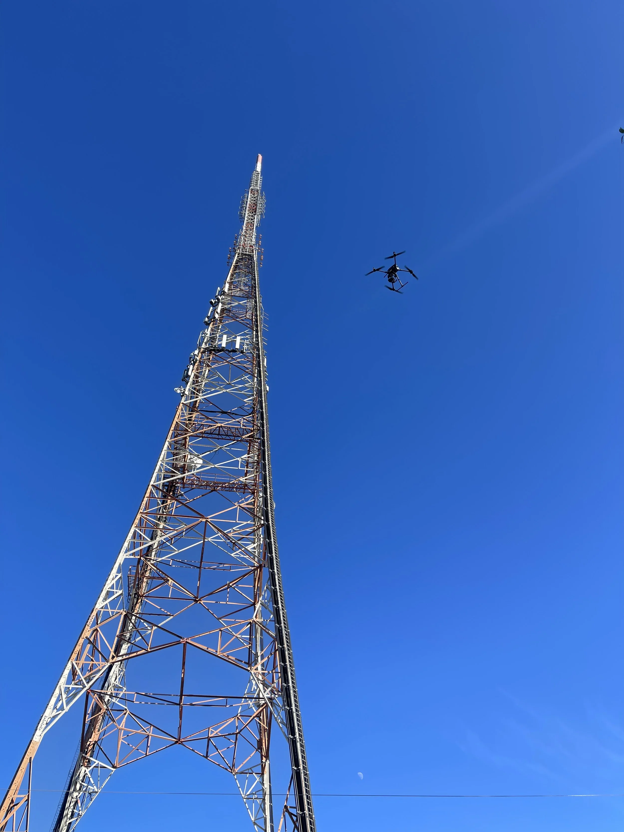 Drone capturing telecommunications tower data for a digital twin cost comparison against traditional climbing inspections