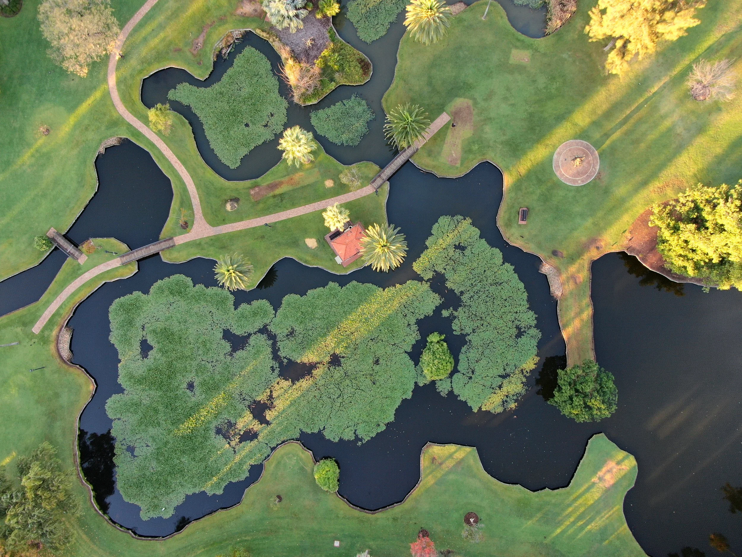 Top-down aerial view of landscaped grounds, waterways and surrounding paths