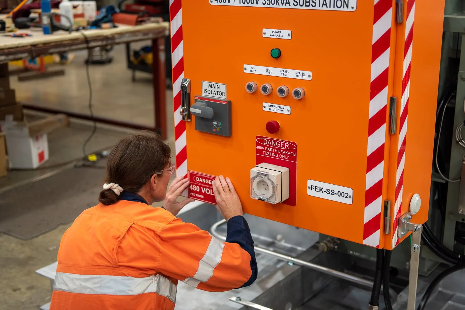 Industrial worker operating electrical control equipment in a workshop