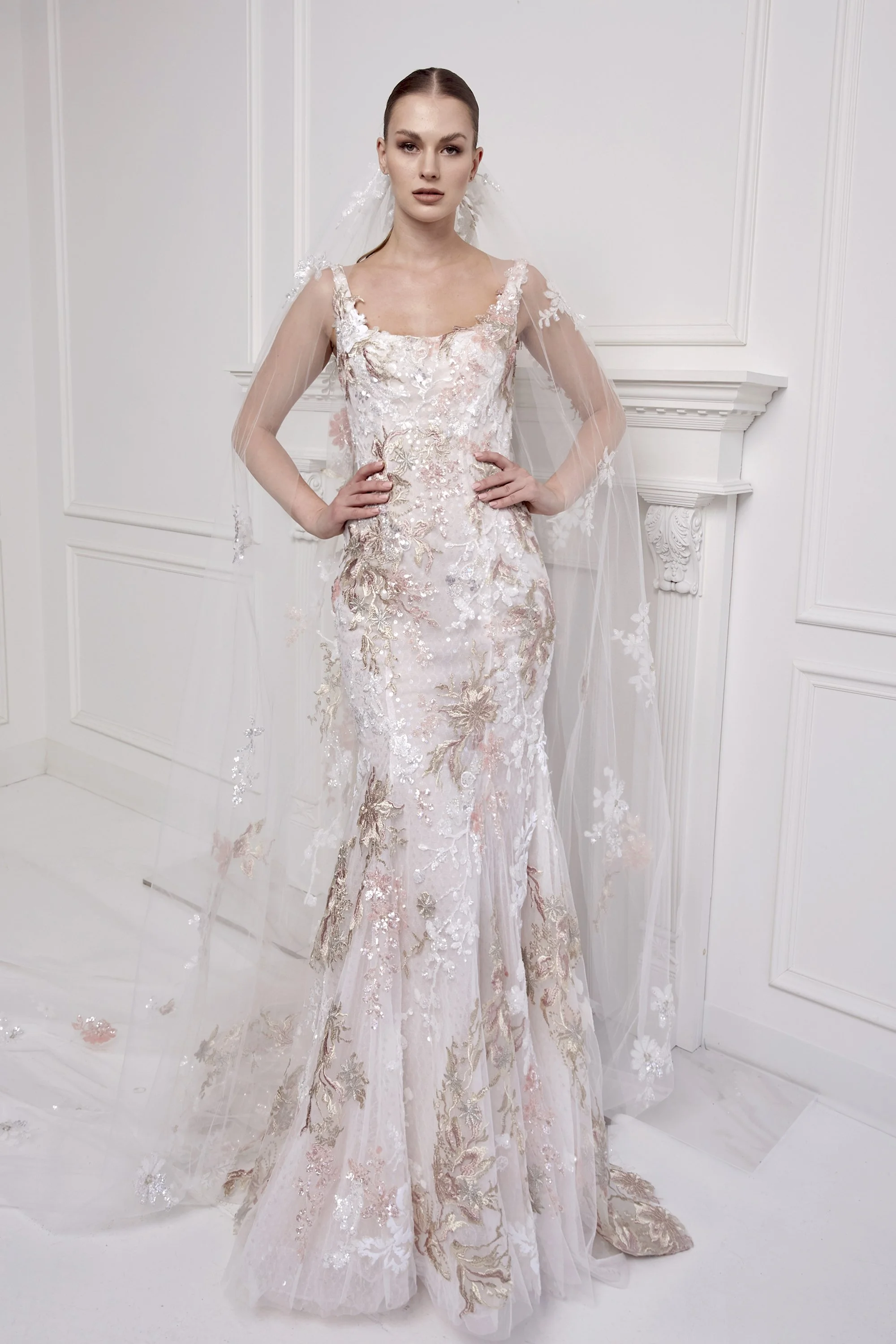 A woman in a wedding dress standing in a white room with decorative wall moldings.