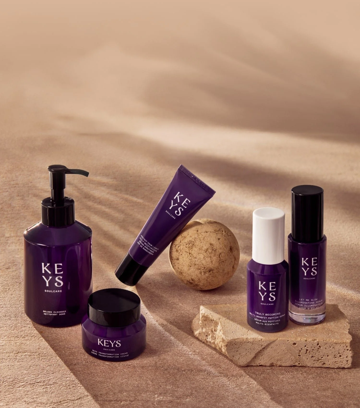 Keys Soulcare skincare products arranged on sand and stone