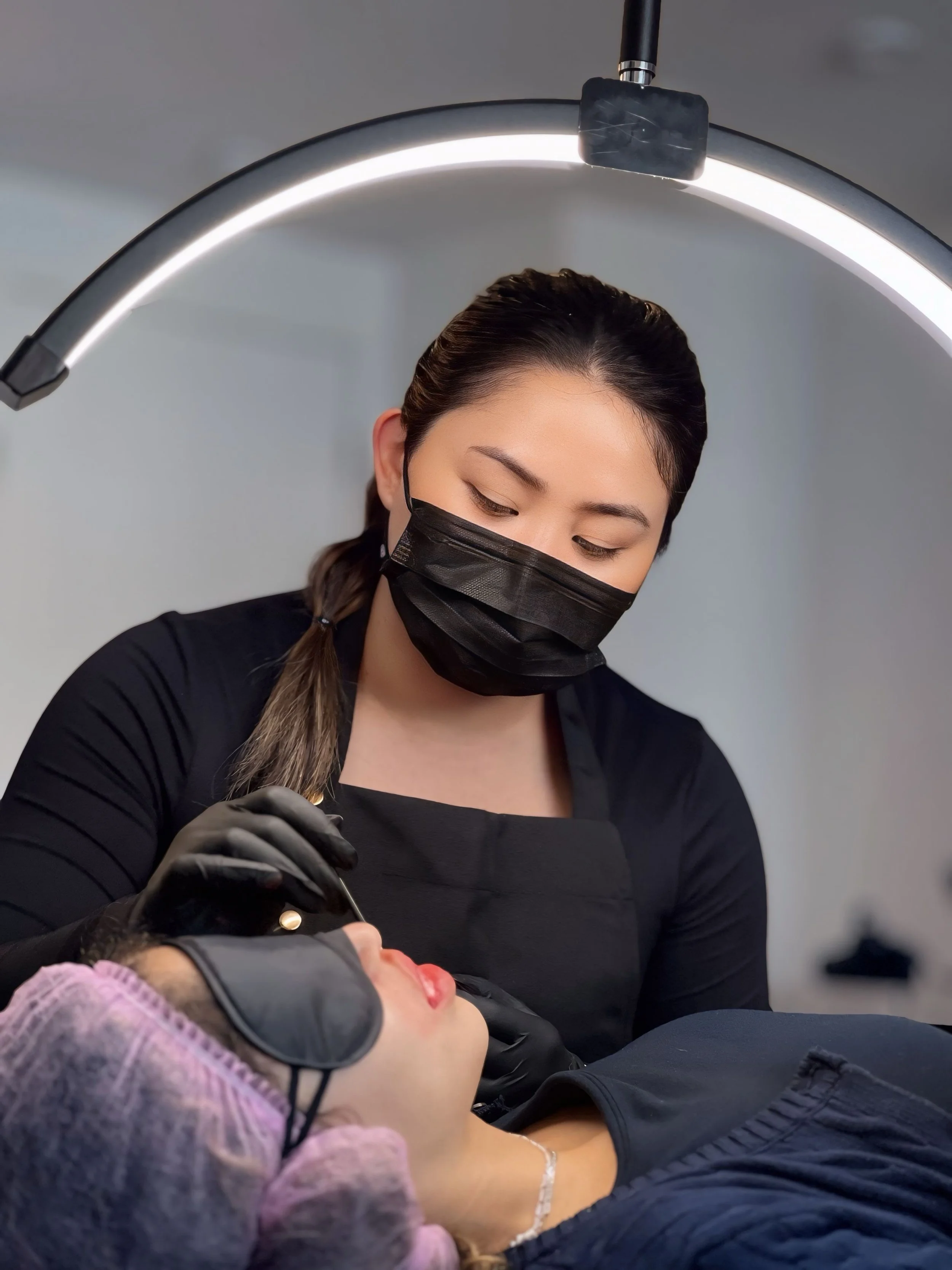 Permanent makeup artist performing a cosmetic tattoo treatment on a client at Akane Studio.