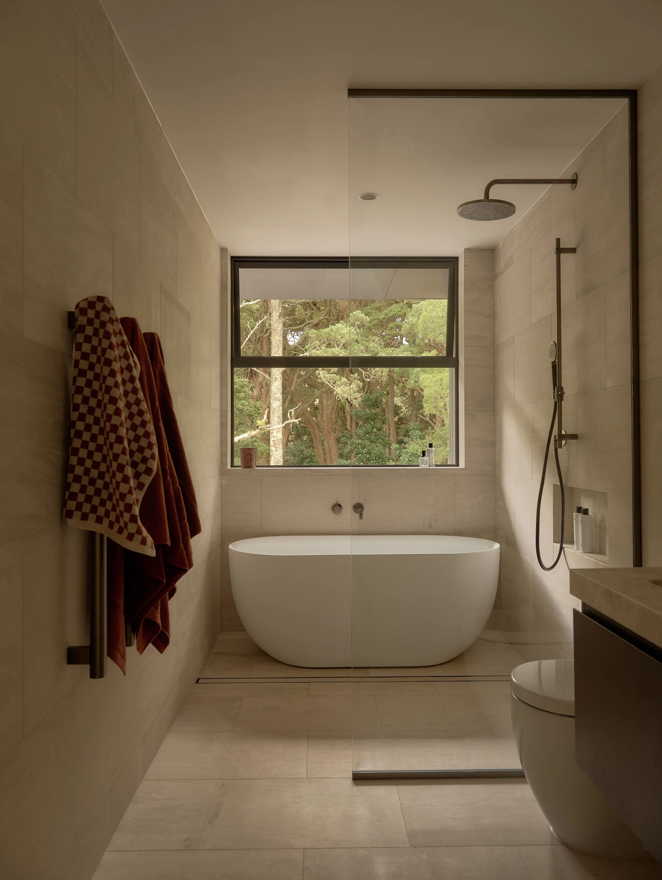 Modern bathroom with a freestanding bathtub, large window overlooking trees, and a walk-in shower with rain showerhead.