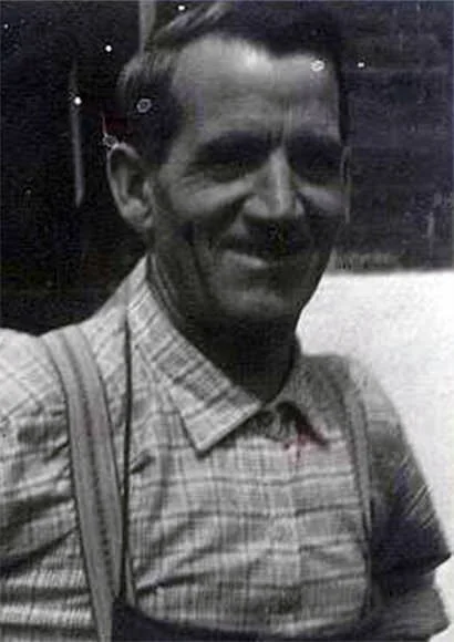 Schwarz-weiß Foto eines lächelnden Mannes mit kurzen Haaren, Hemd mit Karomuster und suspendierten Schulterriemen.