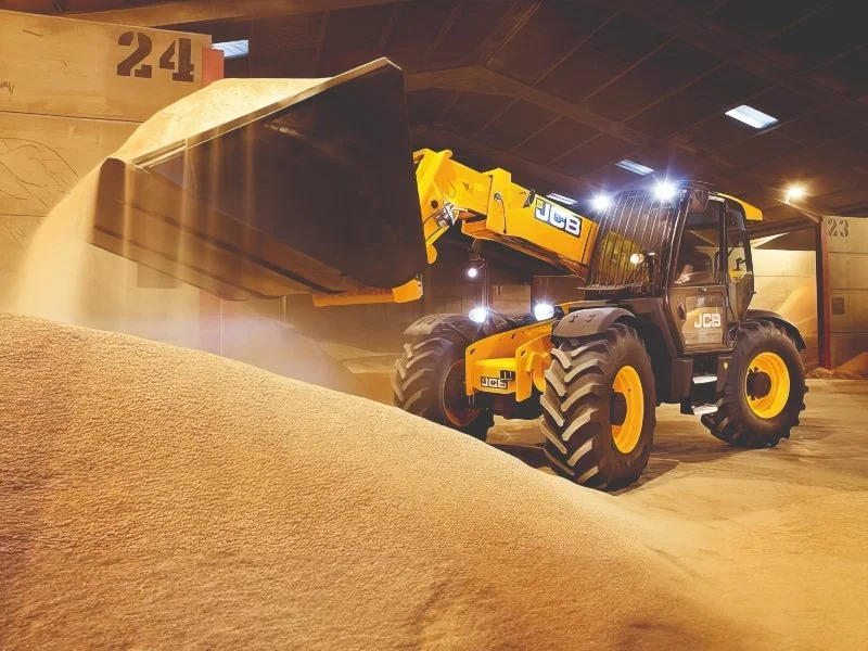 JCB 560-80 telehandler loading grain inside a shed