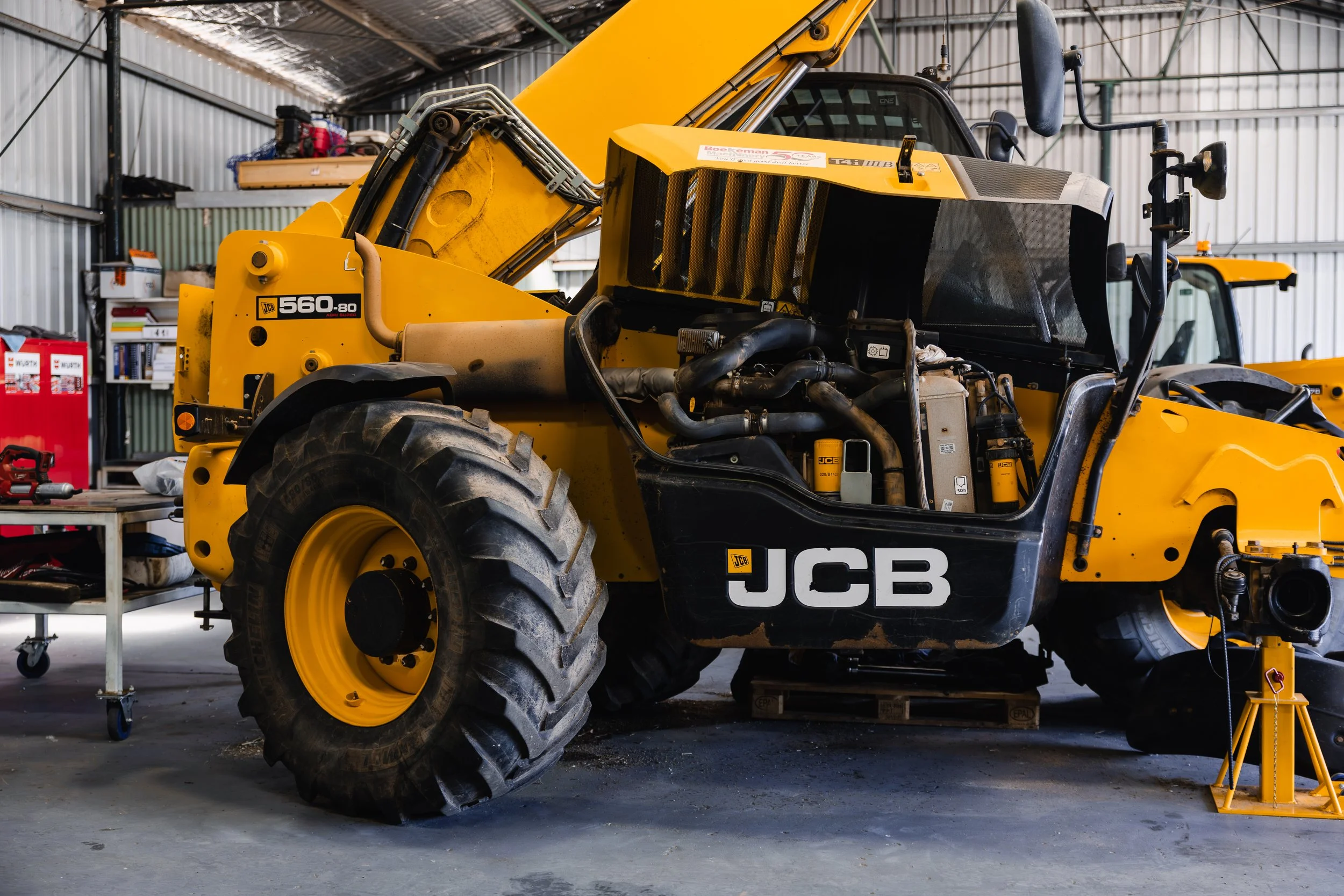 JCB 560-80 telehandler with engine bay open for servicing in the workshop