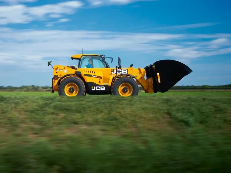 JCB 560-80 Agri telehandler travelling past a grass paddock