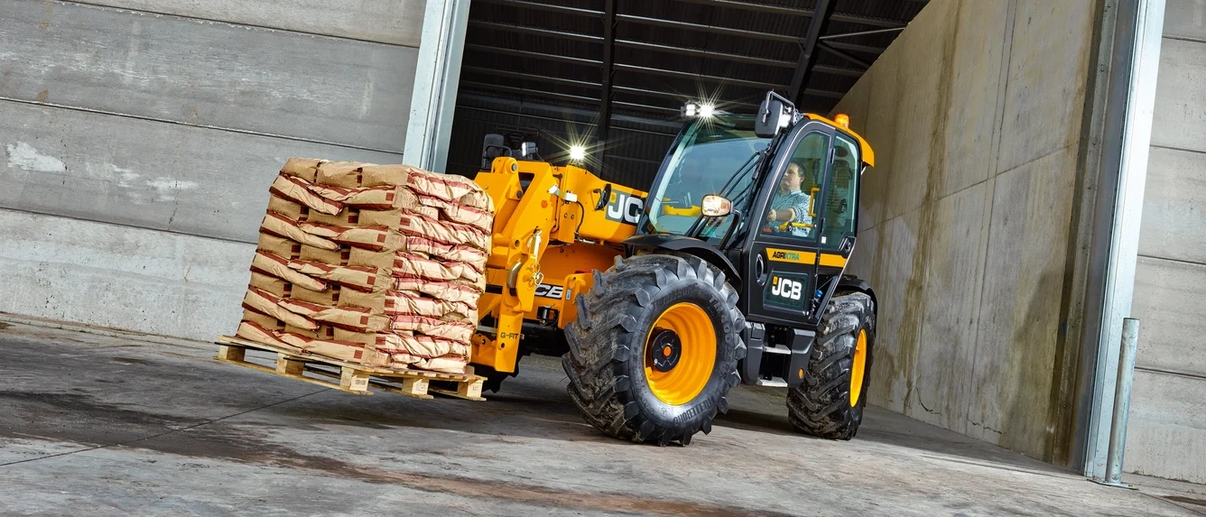 JCB Agri telehandler carrying a pallet of bags in a shed
