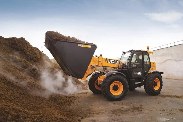 JCB 560-80 Agri Pro telehandler working with a bucket in a farmyard