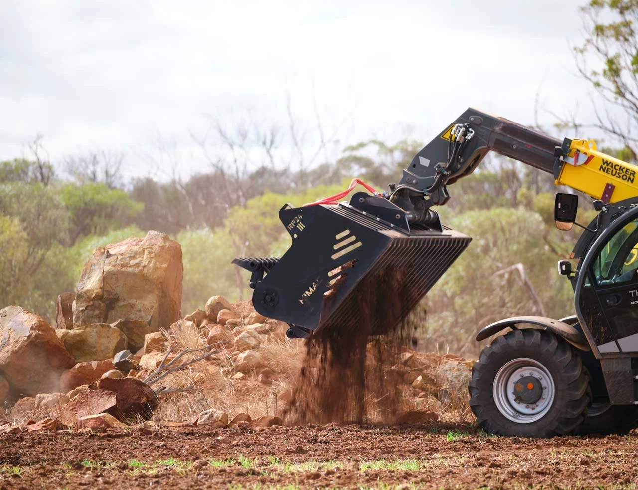 HIMAC rock picker attachment clearing rocks from a paddock