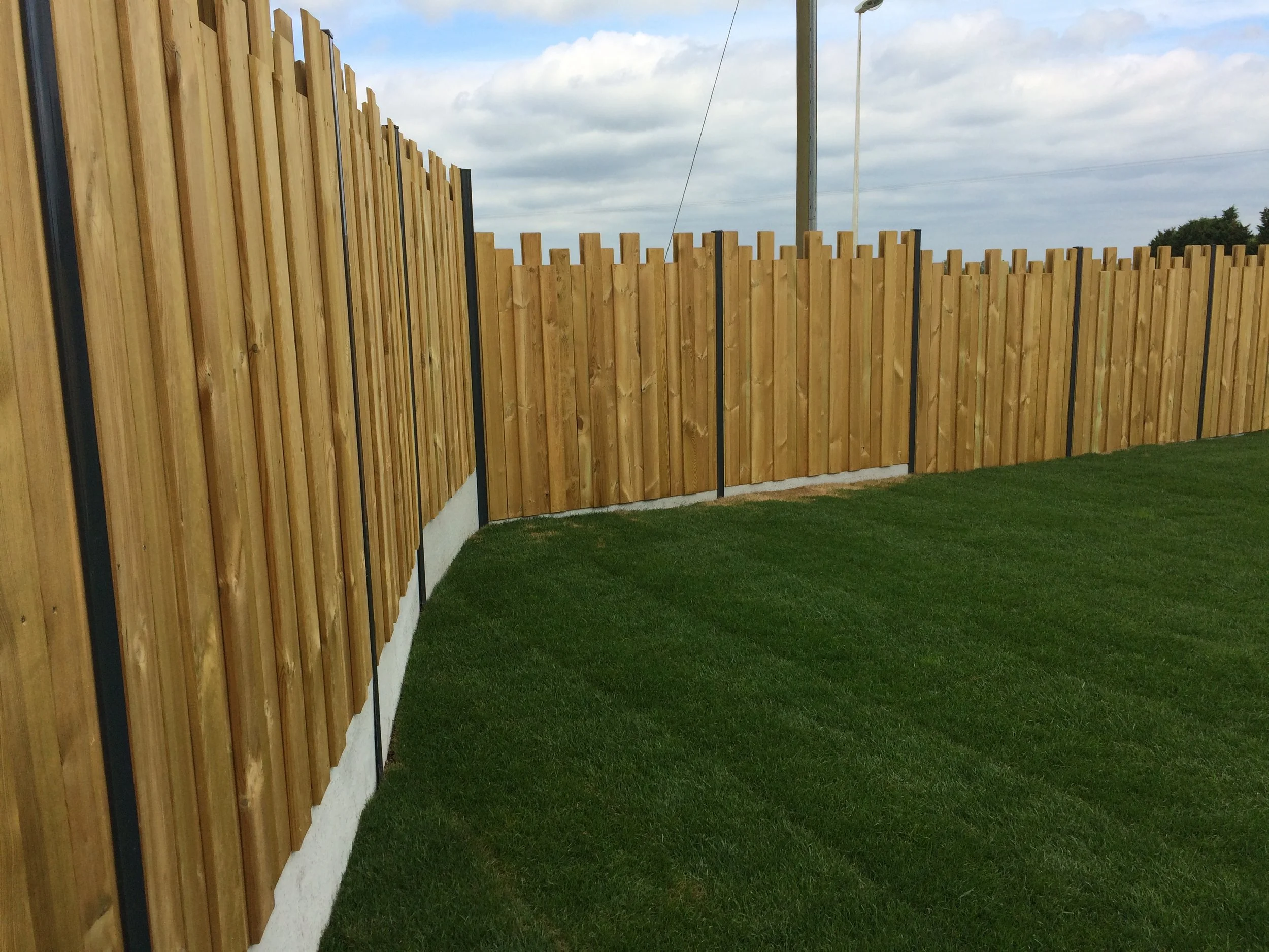 Clôture en bois traité marron avec gazon synthétique
