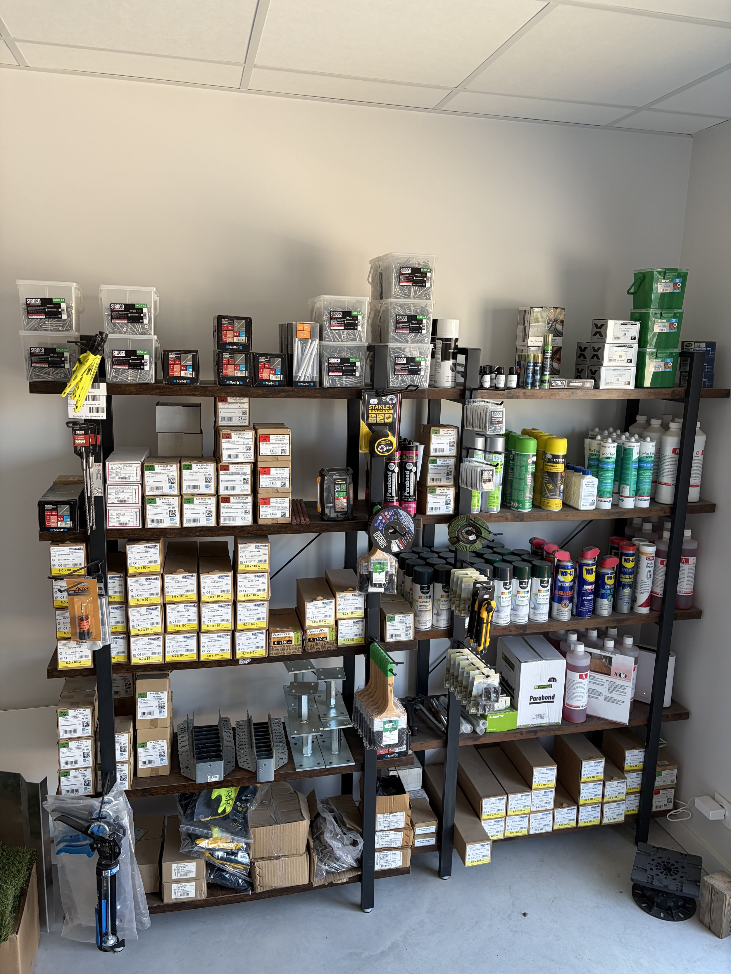Étagère avec divers outils, fournitures et pièces de quincaillerie dans un magasin de bricolage ou d'outillage.