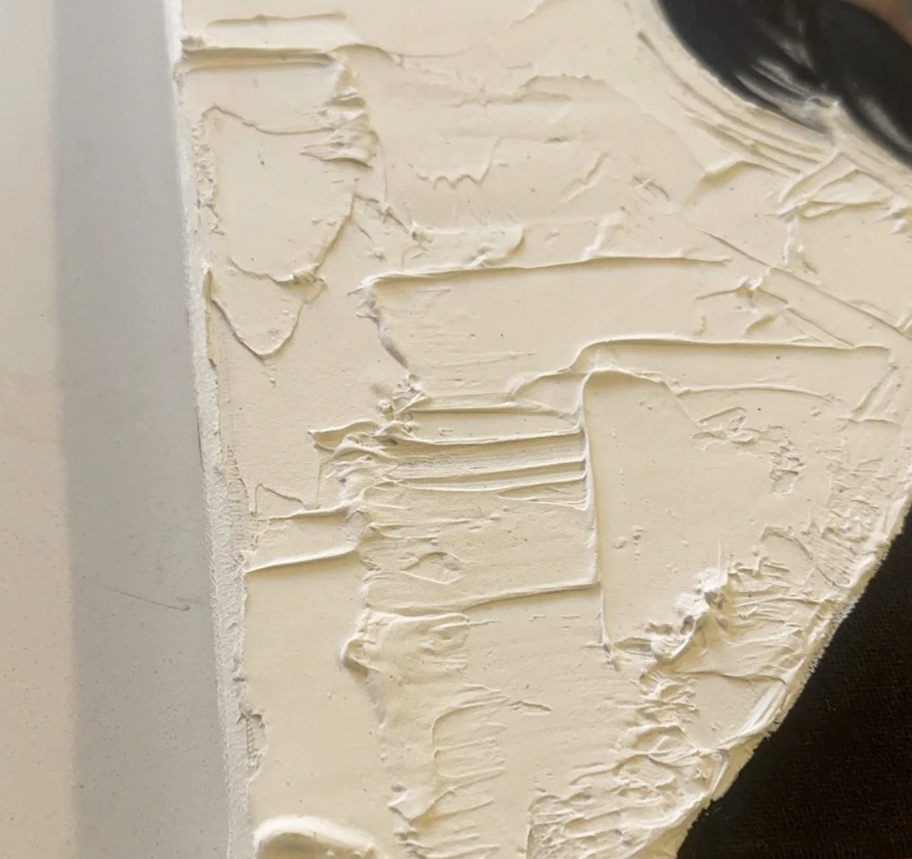 Close-up of a corner of a wall with textured, off-white paint applied with a palette knife.
