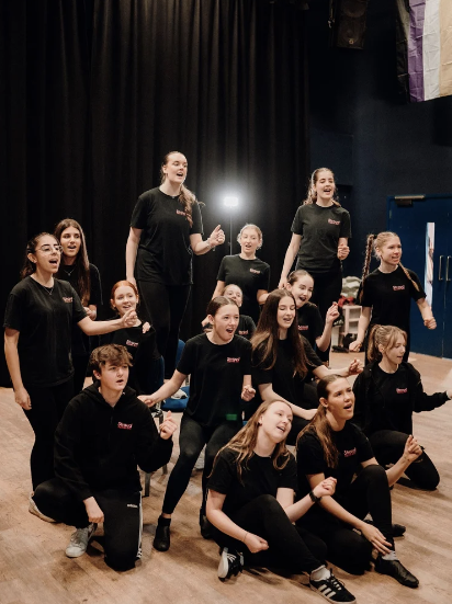 Older Stroud Theatre Arts students singing and performing together during a musical theatre class.