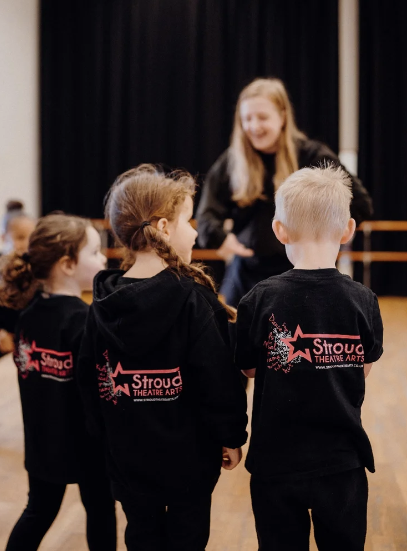 Young children taking part in a Stroud Theatre Arts class with their teacher.