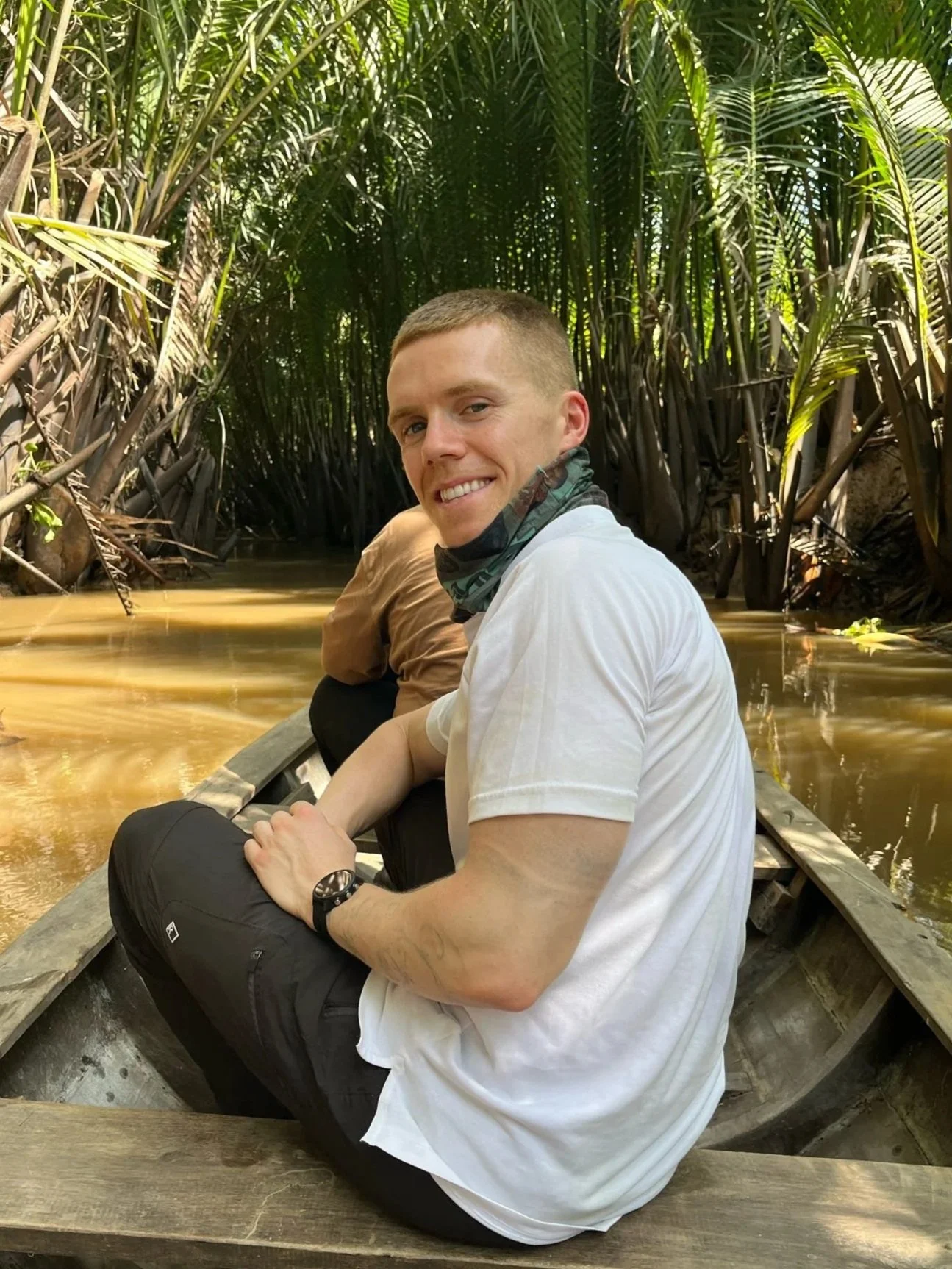 John Donovan, founder of Live Well Nutrition and CORU-registered dietitian, sitting in a wooden boat on a river surrounded by tropical vegetation.