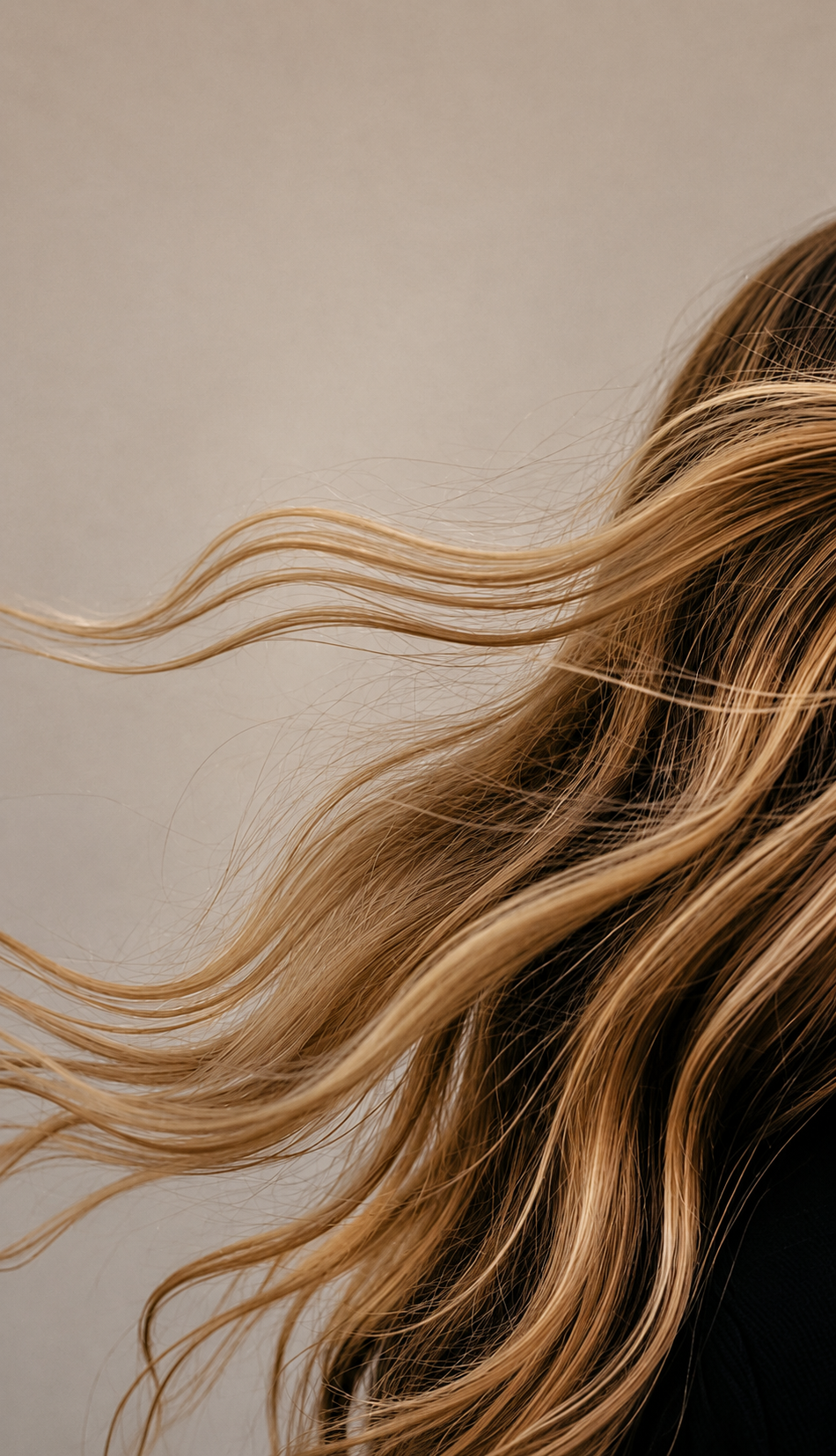 Close-up of wavy, blonde hair against a neutral background.