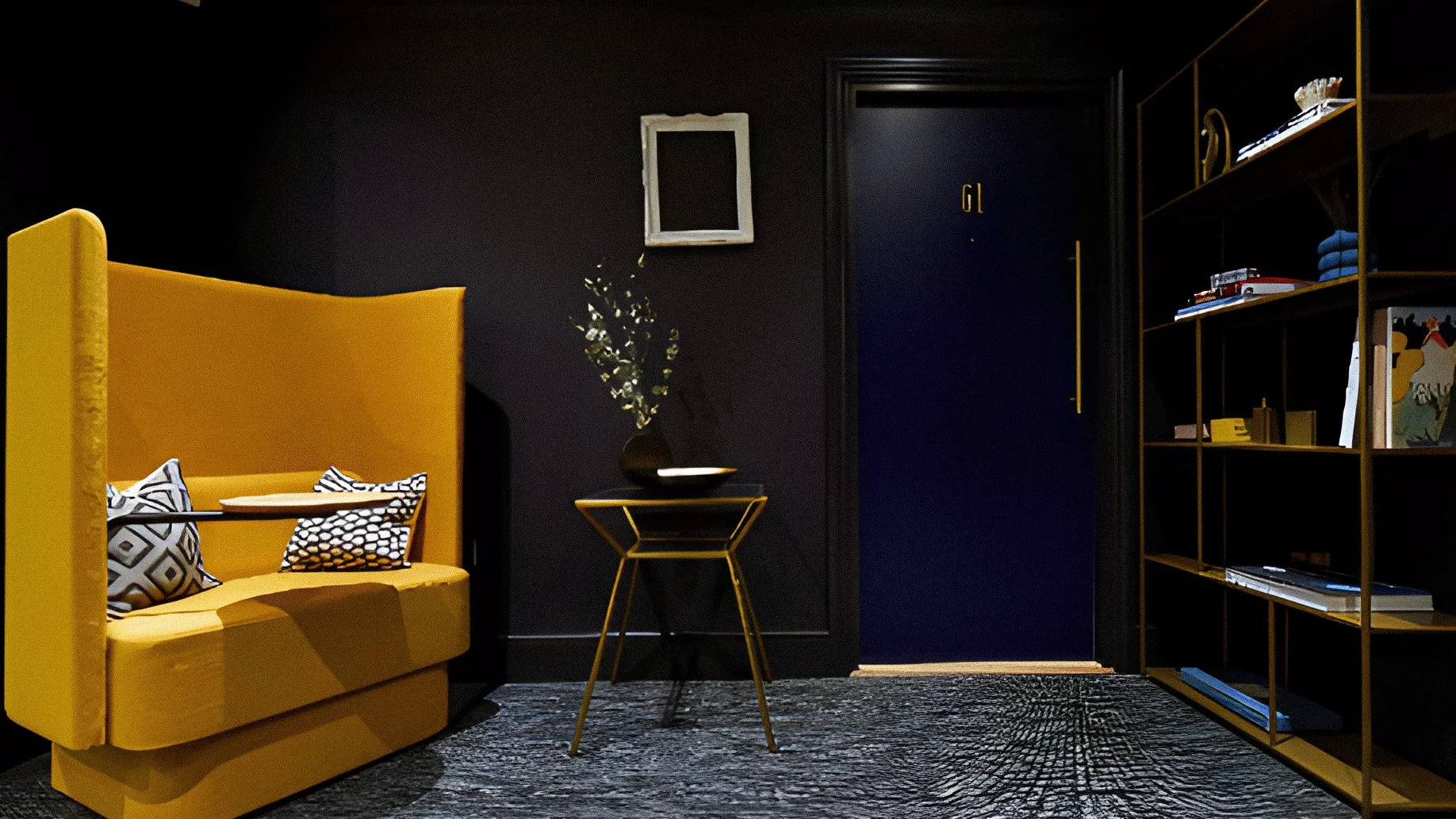 Modern living room with black walls, yellow furniture, and gold accents. A yellow sofa with black and white patterned pillows is on the left, and a small yellow side table with a black vase and decorative branches is in the middle. A dark door with the number 19 in gold is in the center, and a black and gold bookshelf with books and decorative items is on the right.