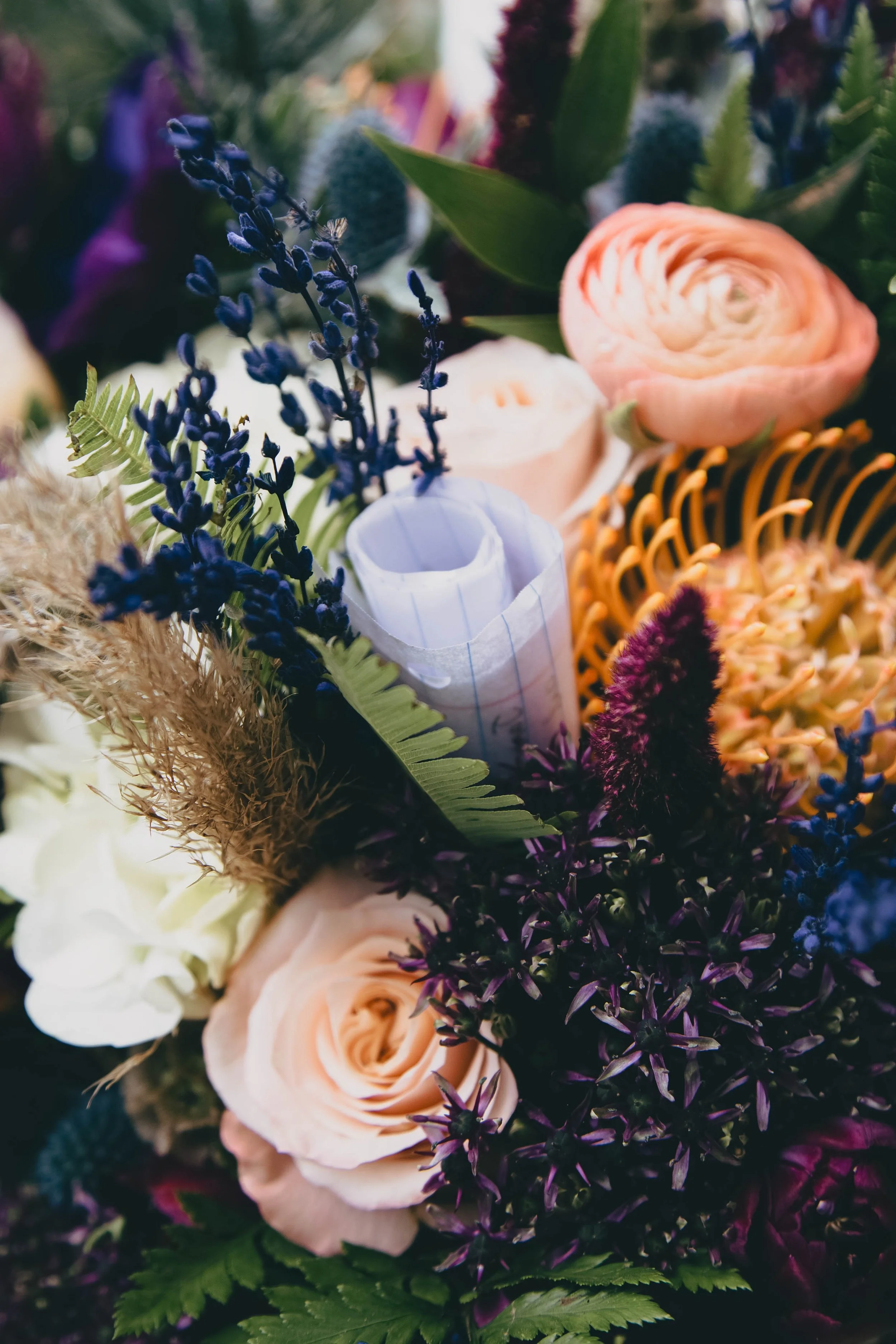 Close-up of a mixed bouquet of flowers featuring peach roses, purple lavender, and other greenery.