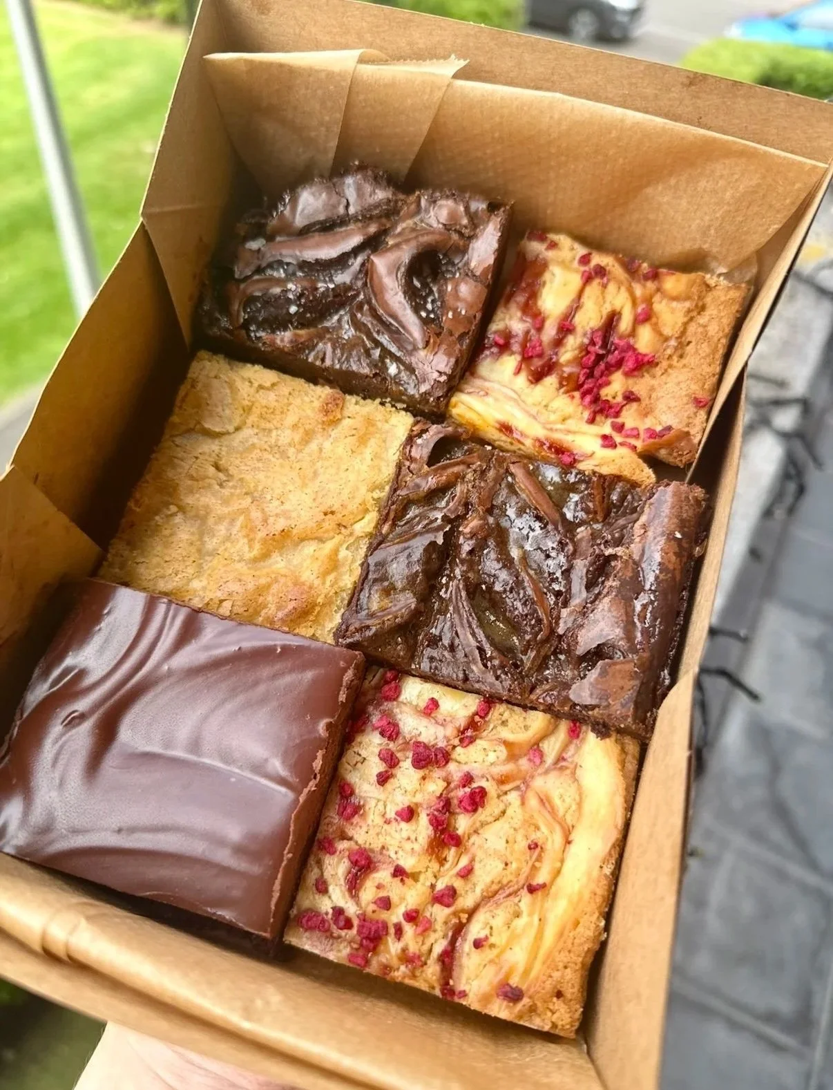 A box of six assorted brownies, featuring raspberry cheesecake blondie, salted caramel brownie, vanilla bean and brown butter blondie and Belgian chocolate ganache brownie.