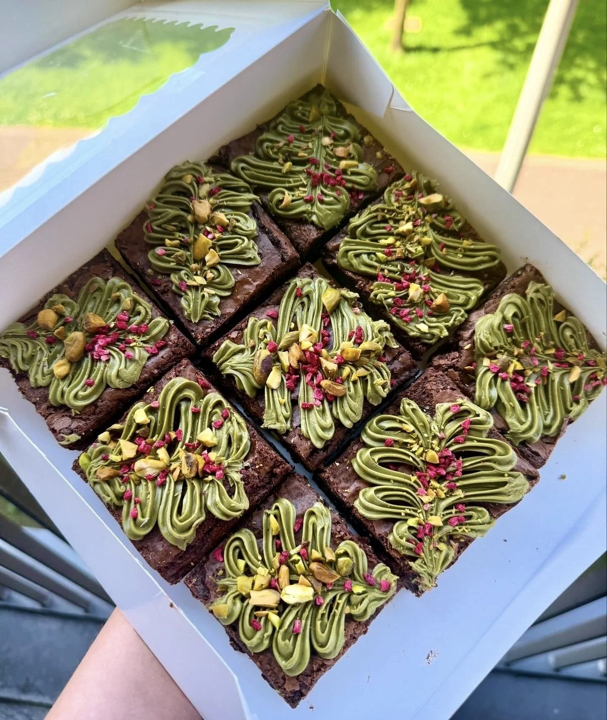 Box of chocolate brownies with pistachio pieces, pistachio cream & freeze dried raspberries.