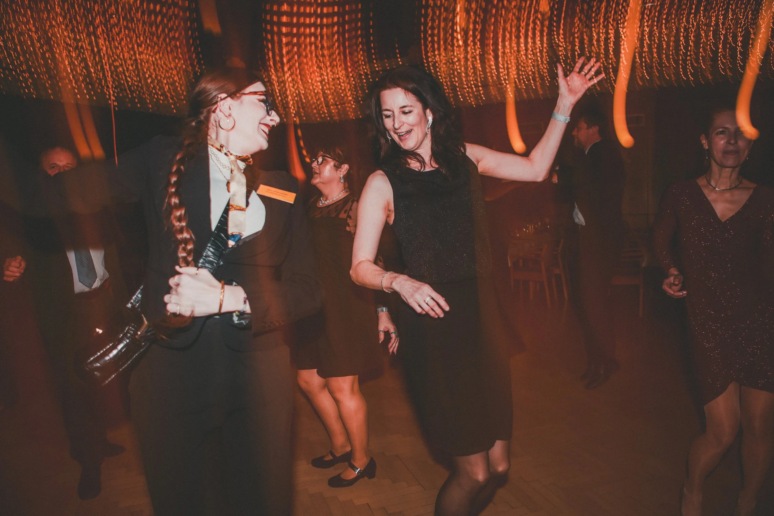 People dancing and enjoying themselves at a lively indoor party or celebration with warm lighting.